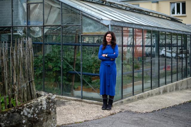 Porträt von Perrine Pouget von der asbl Ôpen vor einem Gewächshaus