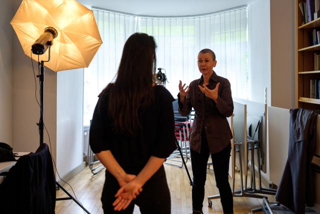 L'artiste Cristina Nuñez dans son studio photo en train de portraiter une femme qu'on voit de dos