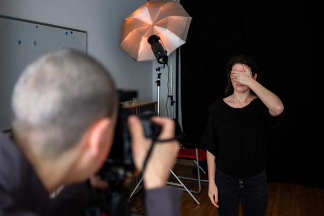 L'artiste Cristina Nuñez dans son studio photo en train de portraiter une femme qu'on voit de dos