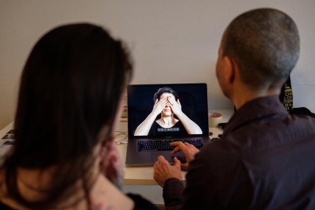 Die Künstlerin Cristina Nuñez in ihrem Fotostudio, vor einem Computerbildschirm stehend, zusammen mit einer anderen Frau. Sie sind von hinten zu sehen.