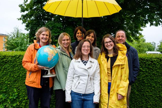 Portraits of 7 people from the team of the Ligue pour la santé mentale, each holding a yellow umbrella.