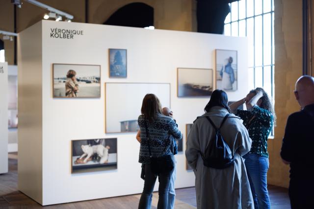 personnes devant un mur avec des photographies encadrées lors d'une exposition