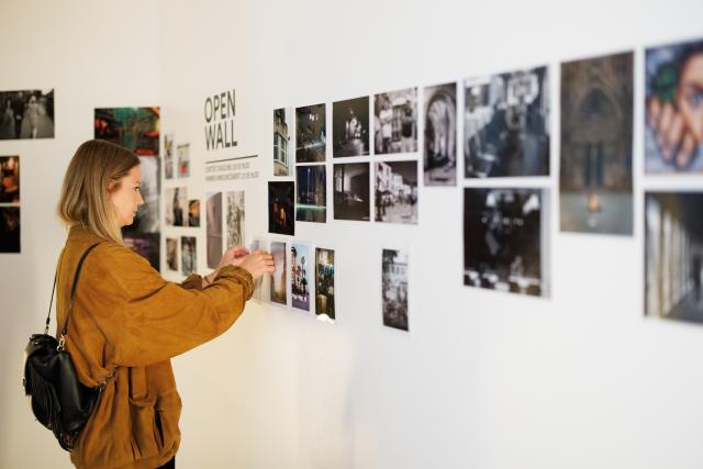 jeune femme qui place une photographie sur un mur pour participer à une exposition