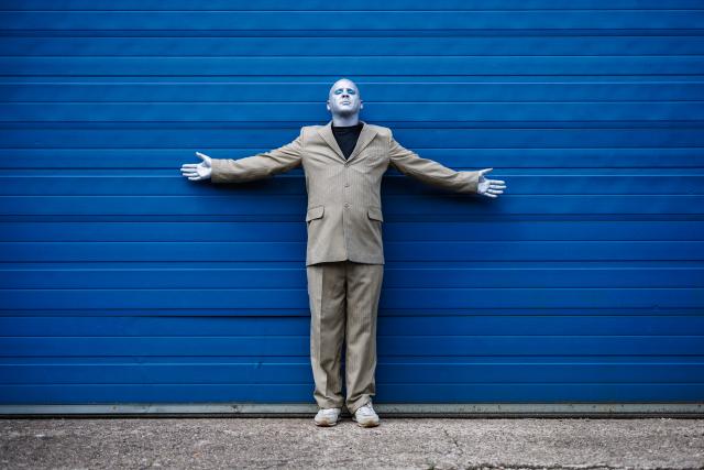 portrait de l'artiste Max Thommes devant un mur bleu.