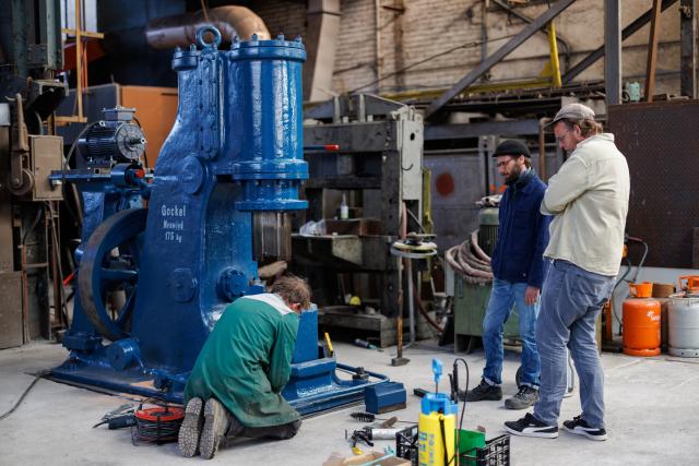 3 hommes travaillent autour d'une machine au tiers-lieu culturel "FerroForum"