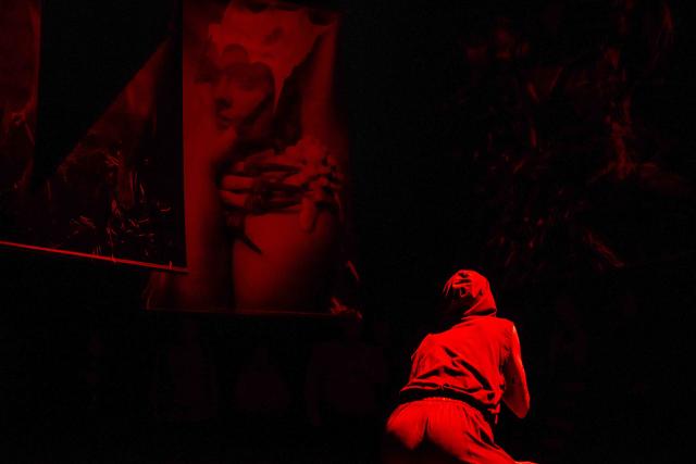 Photo of a person crouching on the ground, bathed in red light.