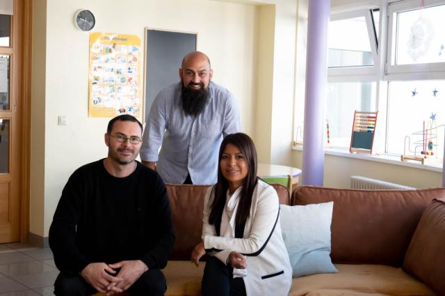 Portrait of Lisset Gabarron, sitting on a sofa with two of her colleagues.