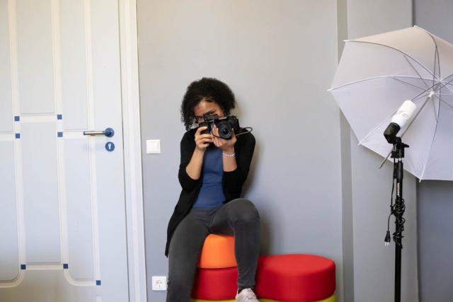 A young woman holding a camera in front of her face