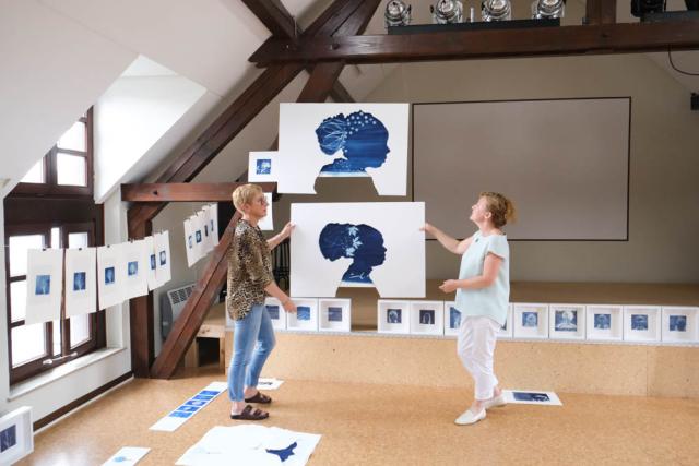 deux femmes en train d'accrocher des images pour une exposition